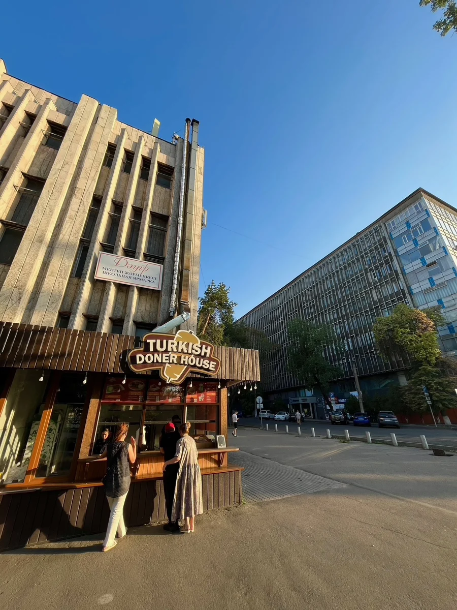 People at a street food stand called 'Turkish Doner House' on an Almaty city corner